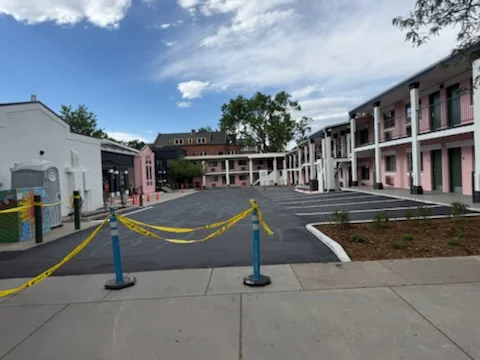 Newly paved black asphalt parking lot with white striping and concrete curbing