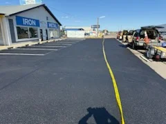 Newly paved commercial parking lot with yellow center line stripe and parked vehicles