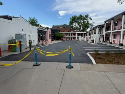 Newly paved asphalt parking lot with yellow line markings and blue bollards