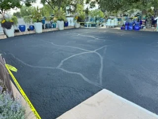 Freshly paved asphalt parking lot with white line markings and directional arrows