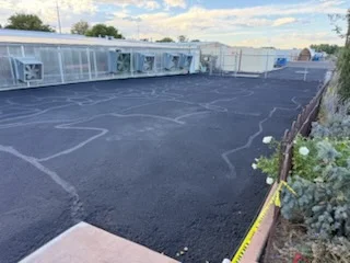Newly paved black asphalt parking lot with white parking space lines and directional markings
