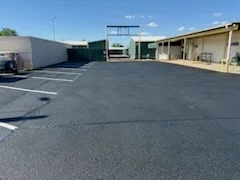 Newly paved commercial parking lot with dark asphalt and industrial buildings
