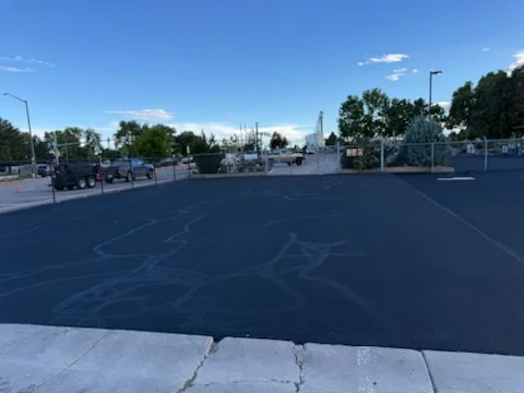 Newly paved commercial parking lot with fresh asphalt and white parking space markings