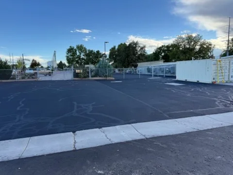 Newly paved commercial parking lot with black asphalt, white striping, and concrete curbing